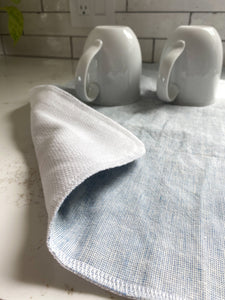 Mugs drip drying on a handmade in the USA mist blue homespun linen dish drying mat, washable dish drying mat, oversized paperless towel, farmhouse kitchen, simple minimalist kitchen, natural fiber drying mat, beautiful simple kitchen accessories, woman owned small shop, small business, made in south dakota, linen and birdseye cotton drying mat