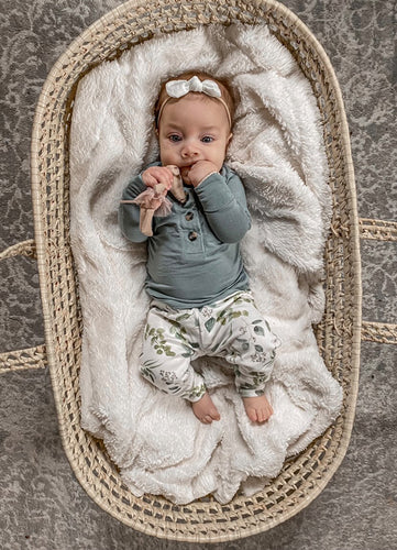 baby in moses basket wearing gender neutral organic small shop handmade leggings in a eucalyptus leaves print. Boho style small shop baby clothes.